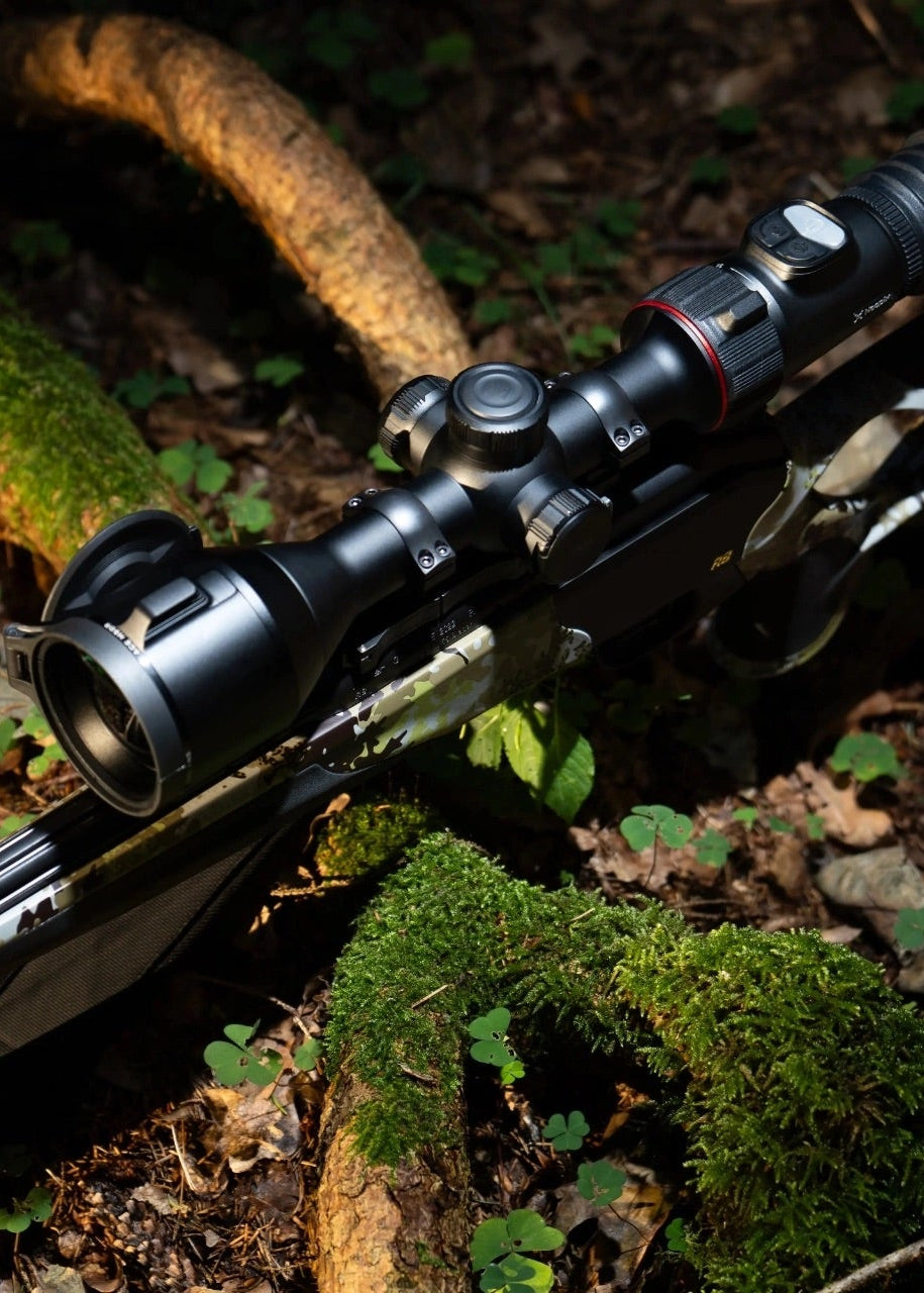 Rifle with scope on a forest floor