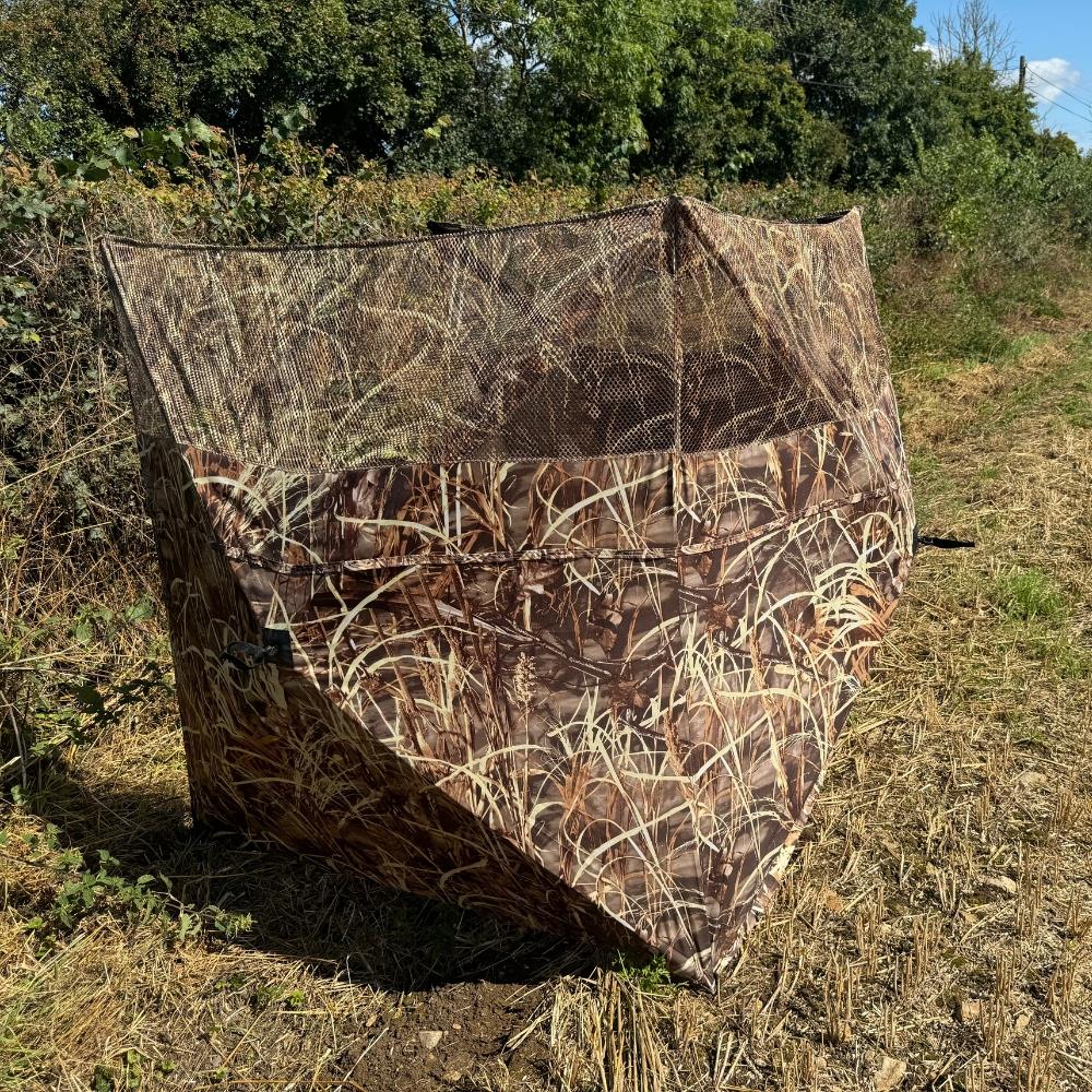 Simon pop-up hunting blind with three-sided stubble and wetland camo, ideal for pigeon shooting and outdoor concealment.
