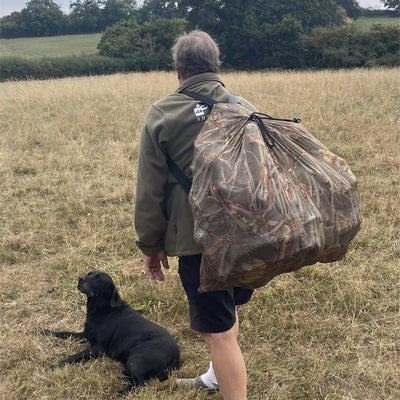 a camouflaged mesh net bag with shoulder straps filled with pigeon decoys